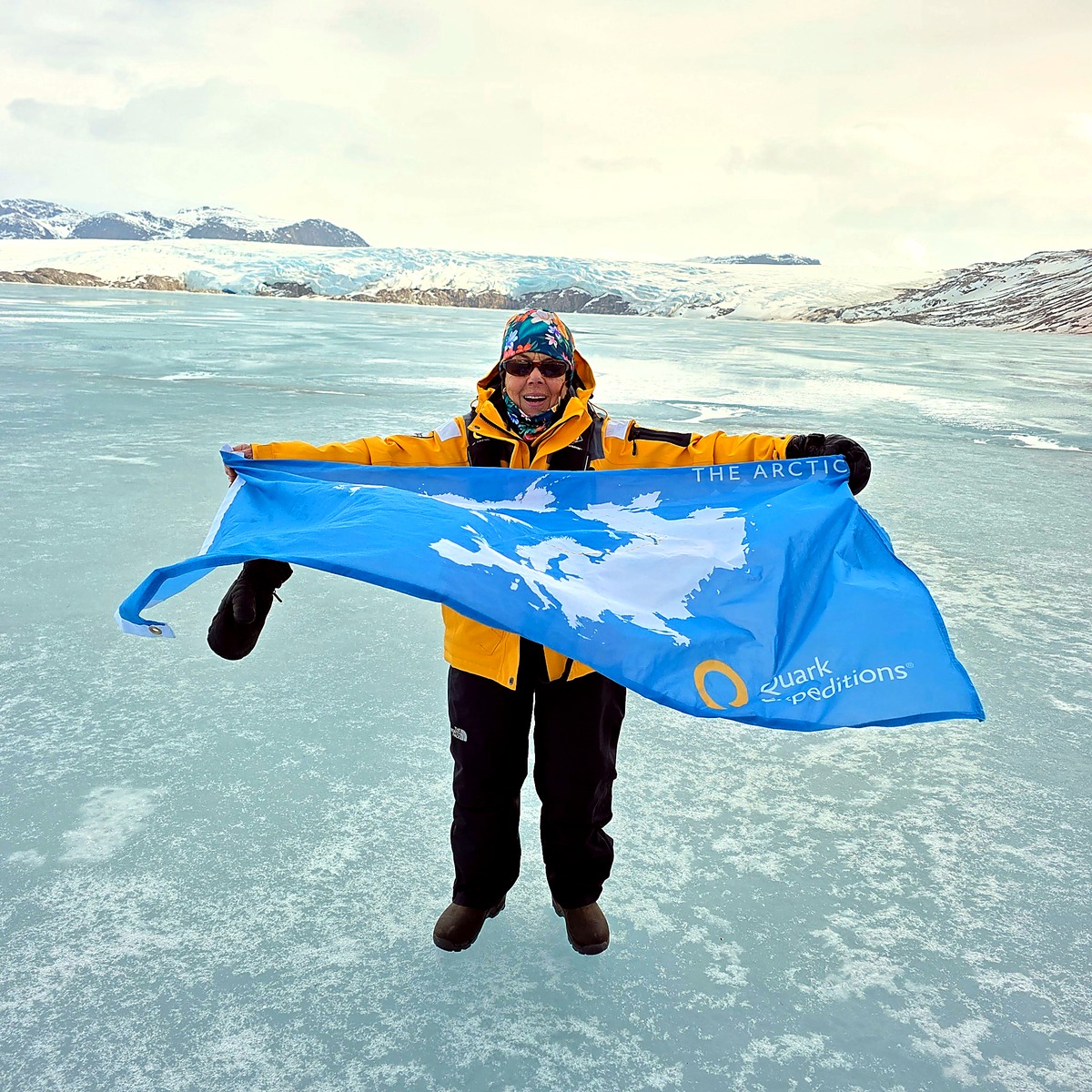 Sue Greene holding The Arctic flag whipping in the wind in Svalbard.